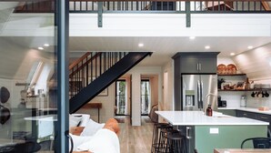 Um amplo loft com pé direito alto, um mezanino, uma área de cozinha e um espaço de refeições com banquetas.