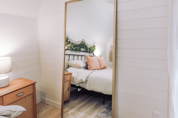 A bedroom with a bed, bedside table, and a mirror.