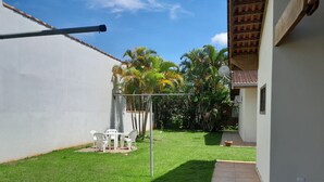 A well-maintained backyard with a patio area, a white fence, and lush greenery. - Residencial Seestern - Ancora (Cananéia)