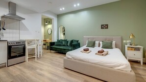 Un dormitorio moderno con una cama grande, un escritorio, un sofá y una kitchenette.