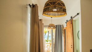 A hallway with a woven pendant light, sliding wooden doors, and a view to an outdoor area with a table and chairs. - Boho Boutique Hotel - Beachfront , Adults Only , Private Pool (Kiwengwa)
