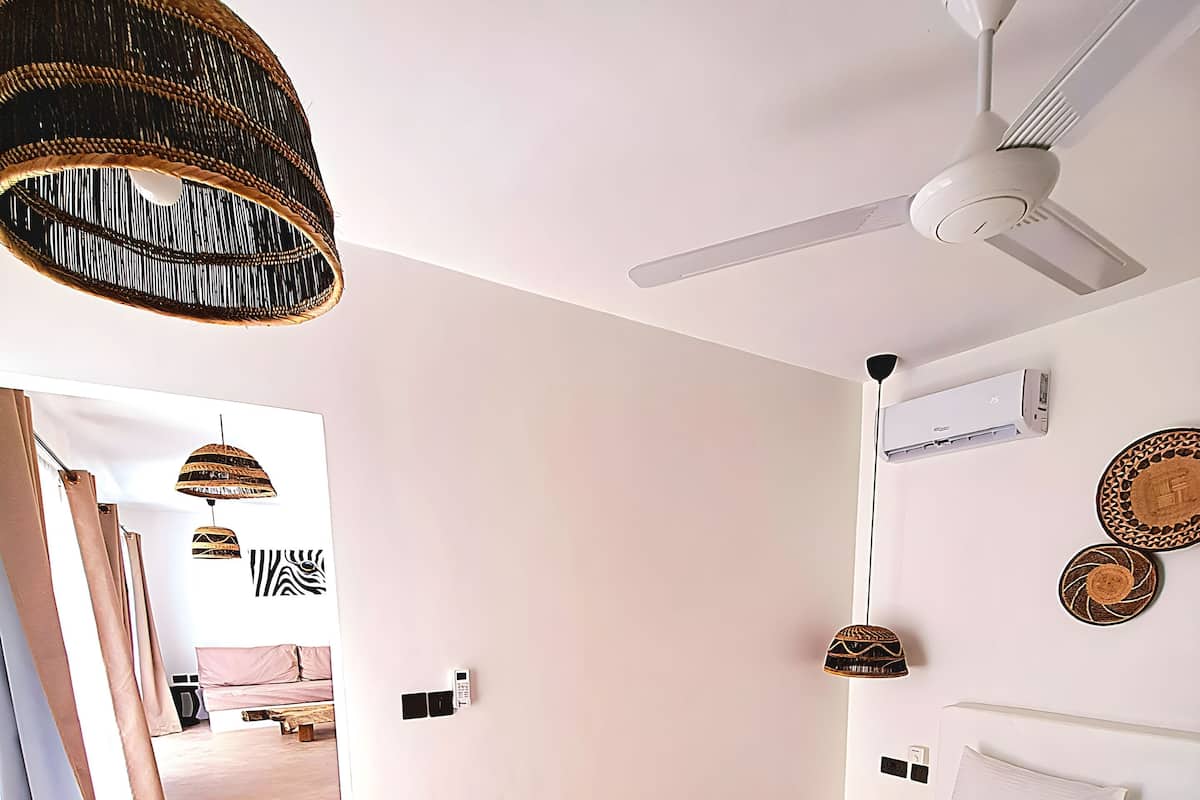 A modern bedroom with a large bed, a ceiling fan, and a hanging light fixture.
