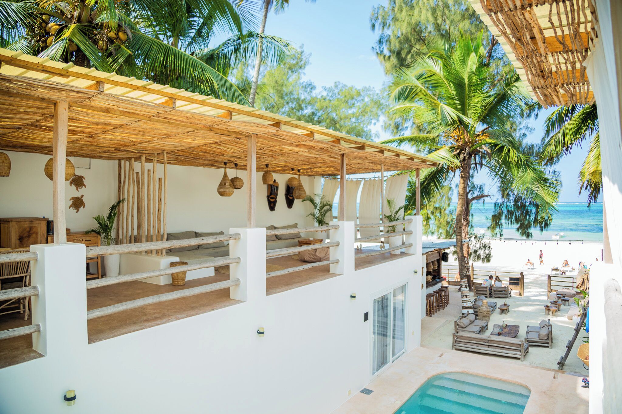 A beachside terrace with a pool, outdoor seating, and a view of the ocean.