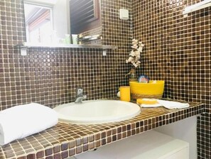 Bathroom features a mosaic-tiled backsplash, a central sink, and a mirror above.