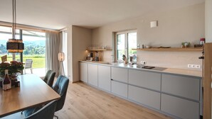 Una cucina moderna con zona pranzo, ampie finestre e vista sull'esterno.