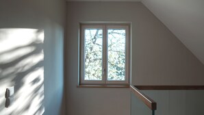 Una moderna scala con ringhiere in vetro, una finestra con vista sugli alberi e un lampadario al soffitto.