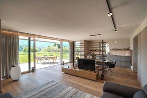 A modern living room with a TV, wooden furniture, and a large sliding glass door leading to a balcony. - Traumhaftes Ferienhaus Eibiswald / Südsteiermark - Am Lateinberg (Eibiswald)