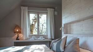 Una camera da letto con un letto, un comodino, una lampada, una finestra con tende e una testiera in legno.