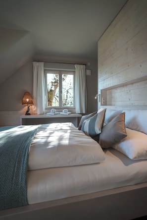 Ein Schlafzimmer mit einem Bett, einem Nachttisch, einer Lampe, einem Fenster mit Vorhängen und einem hölzernen Kopfteil.