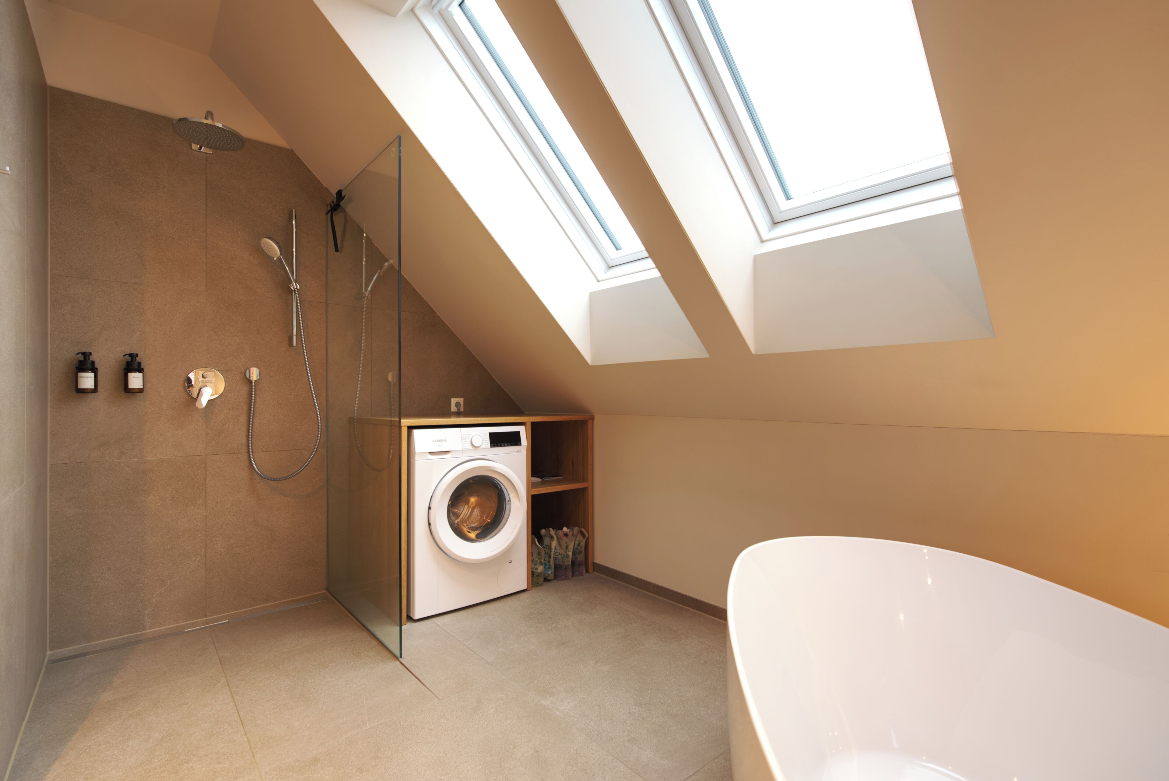 A modern bathroom with a skylight, a washing machine, and a bathtub.