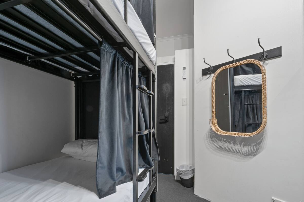 Habitación con literas, espejo y puerta.
