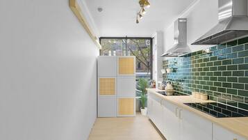 Una cocina moderna con armarios blancos, salpicadero de azulejos verdes y encimera de madera.