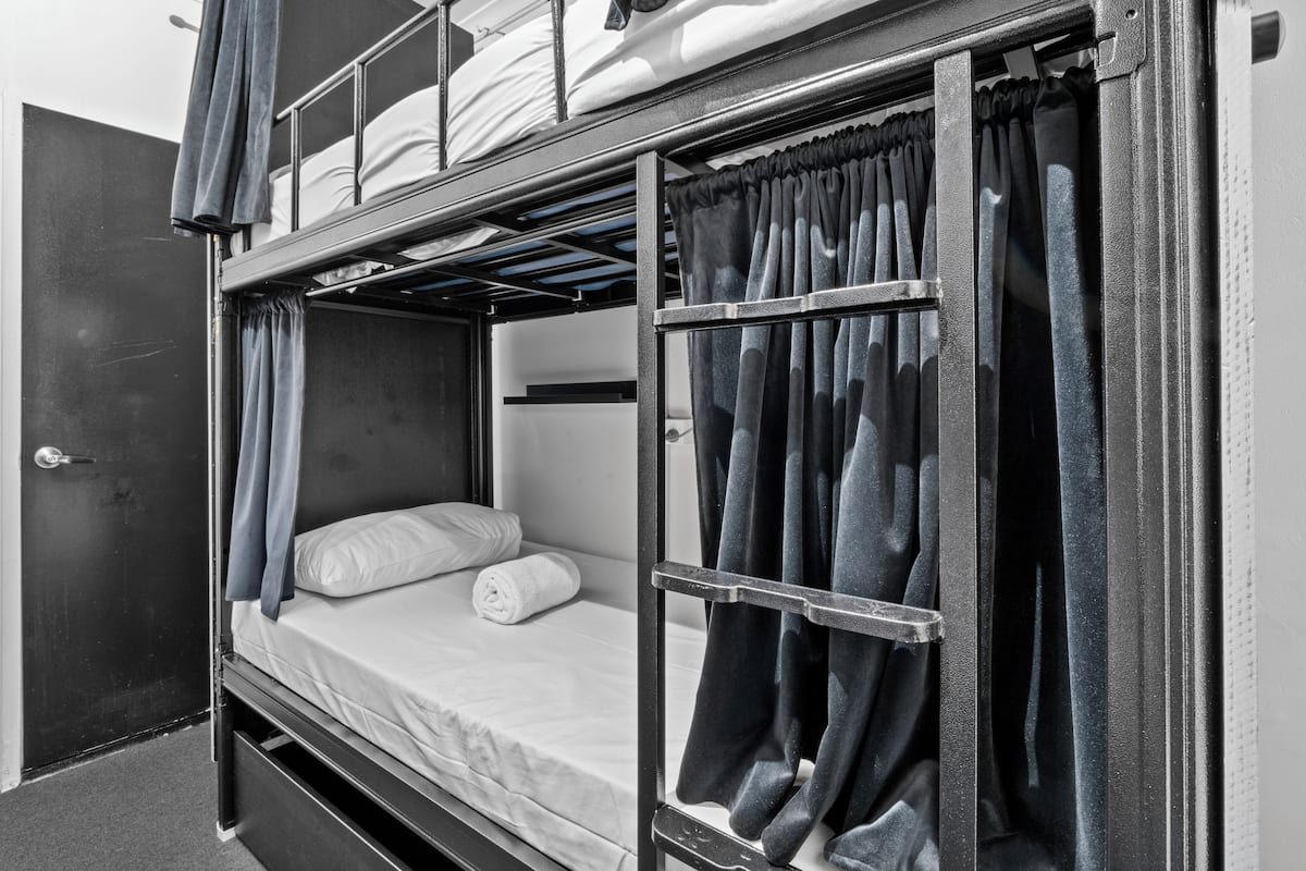 Una cama litera con una cama inferior, una puerta y cortinas.