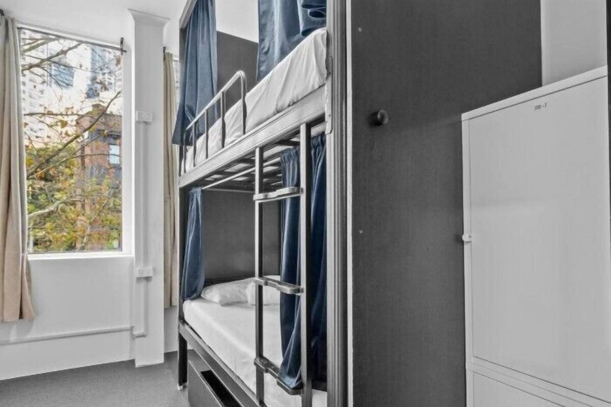 Habitación con literas, una ventana, cortinas y un armario blanco.