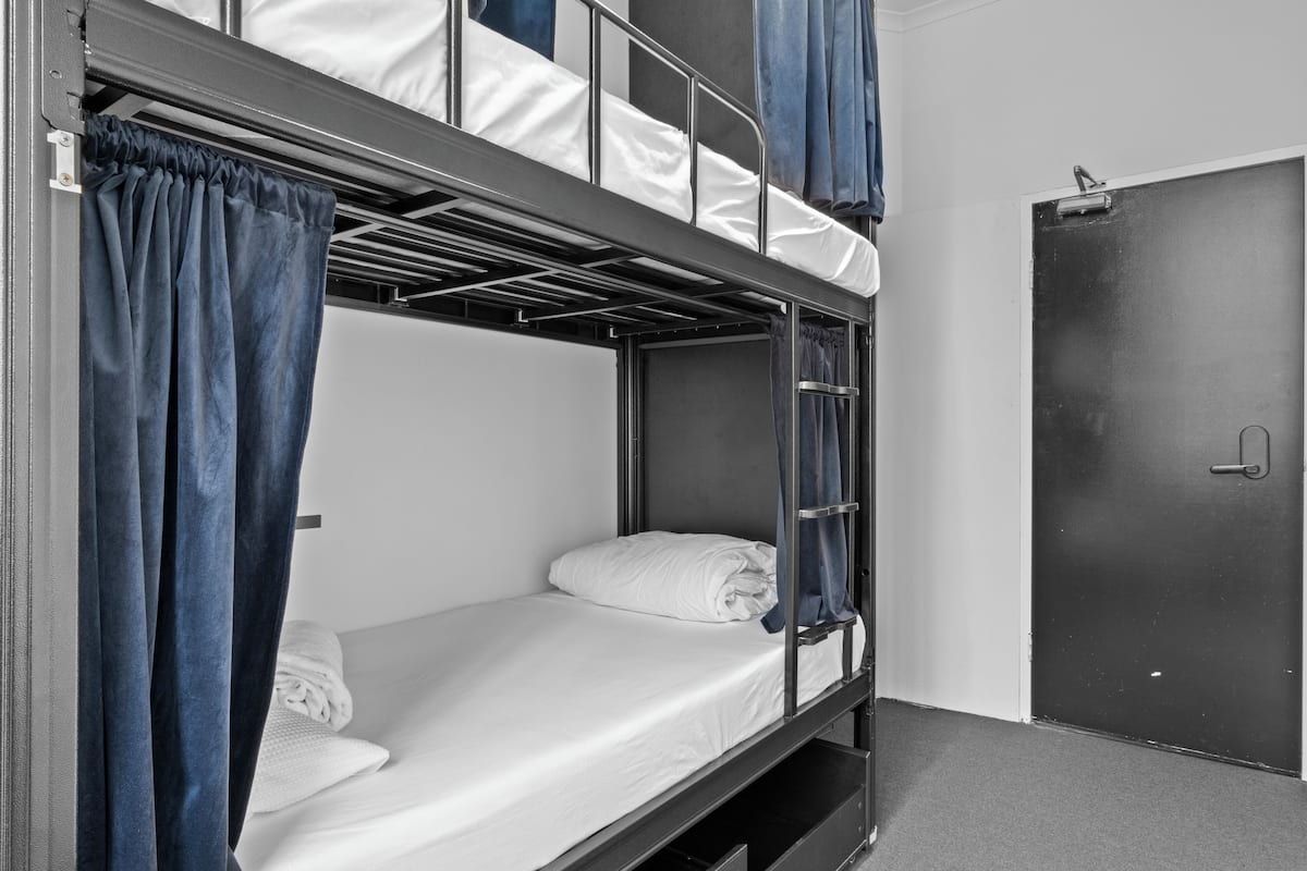 Habitación con literas, una puerta y un pequeño cajón para guardar objetos.