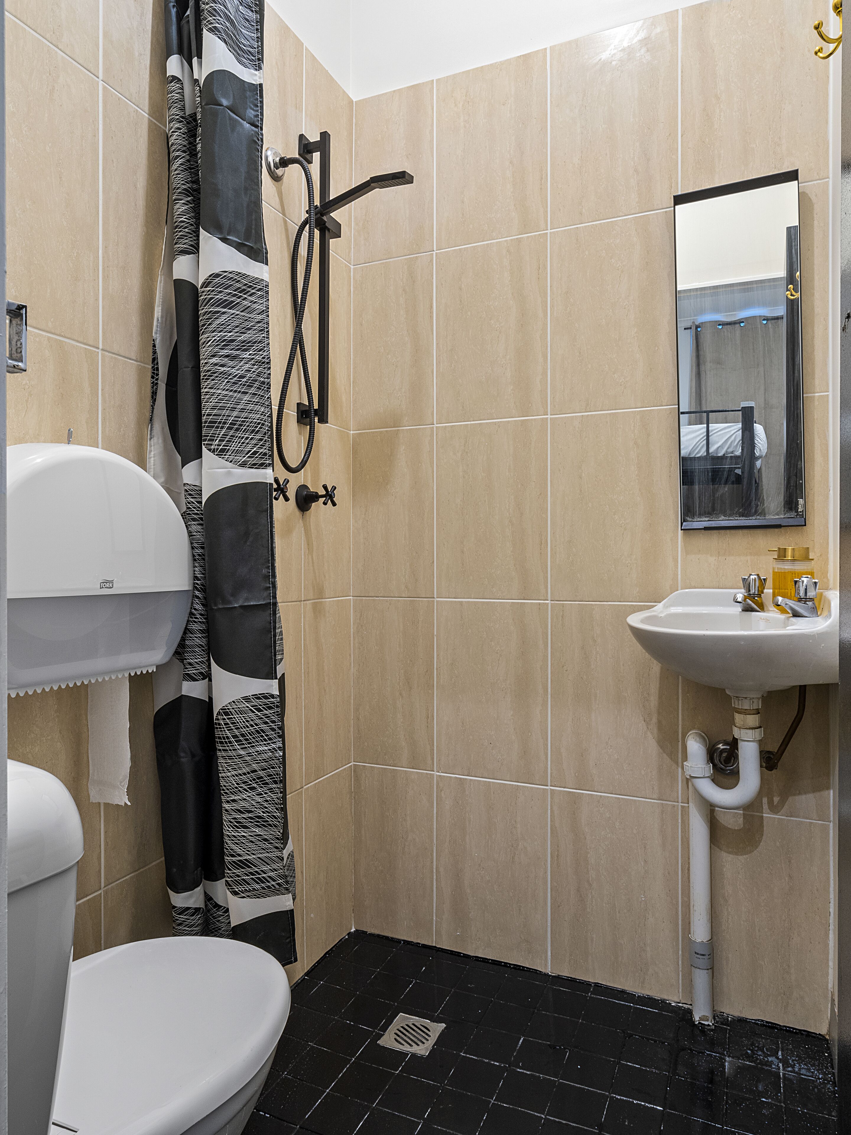 A bathroom with a toilet, shower, and sink.
