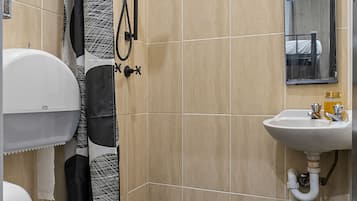 A bathroom with a toilet, shower, and sink.