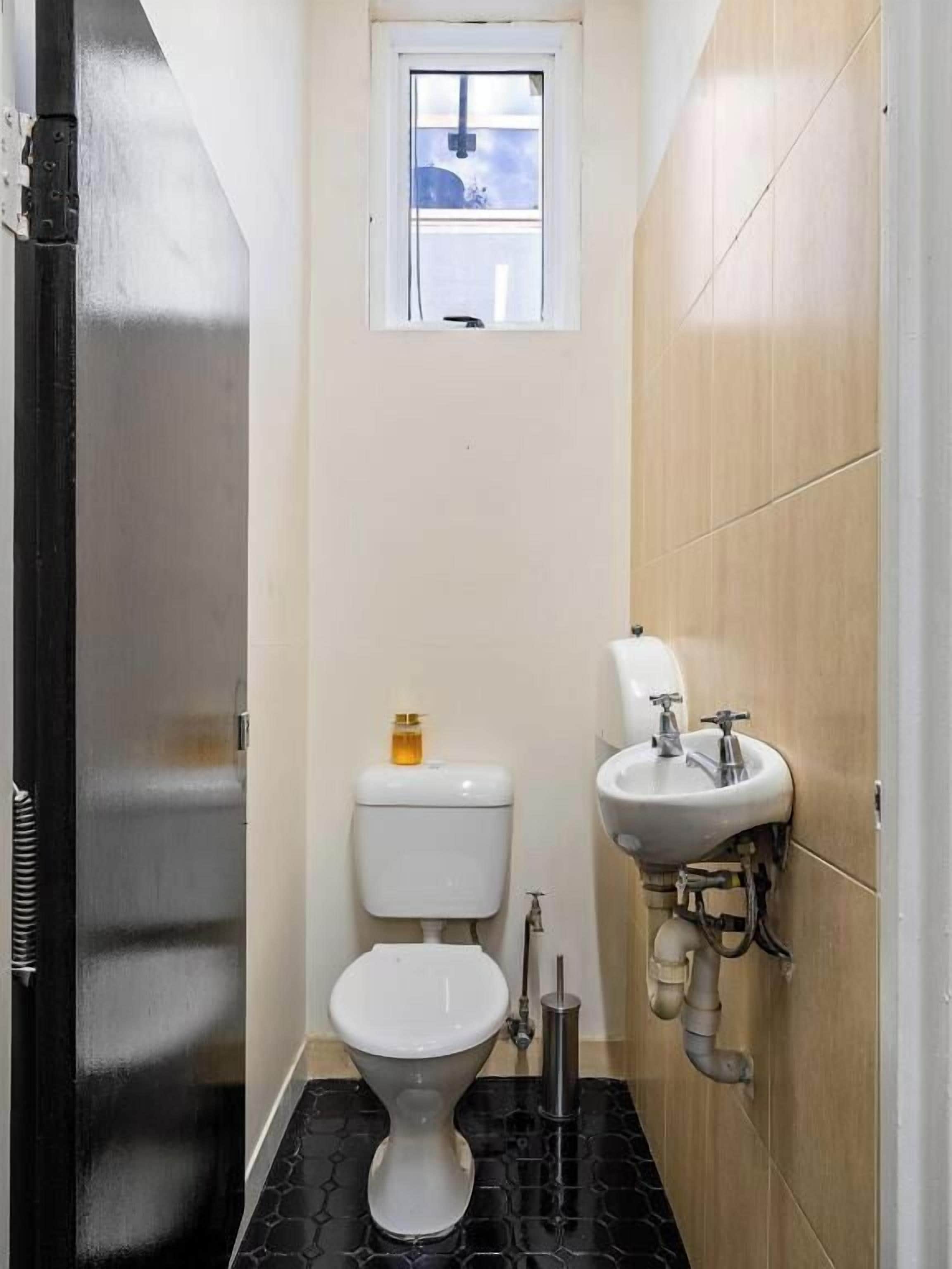 Un baño pequeño con inodoro, lavamanos y ventana.