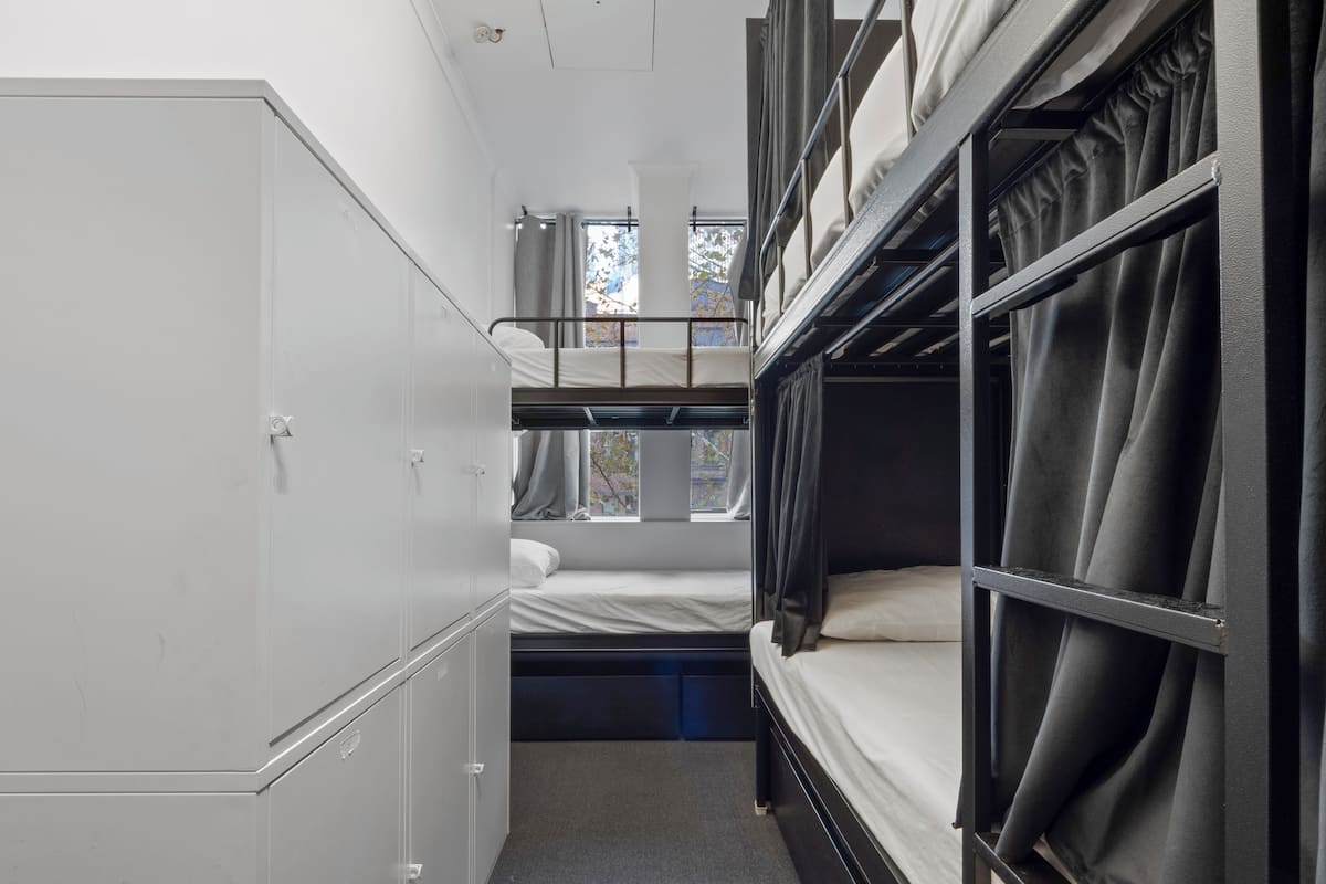 Habitación tipo dormitorio con literas, un armario y una ventana con cortinas.