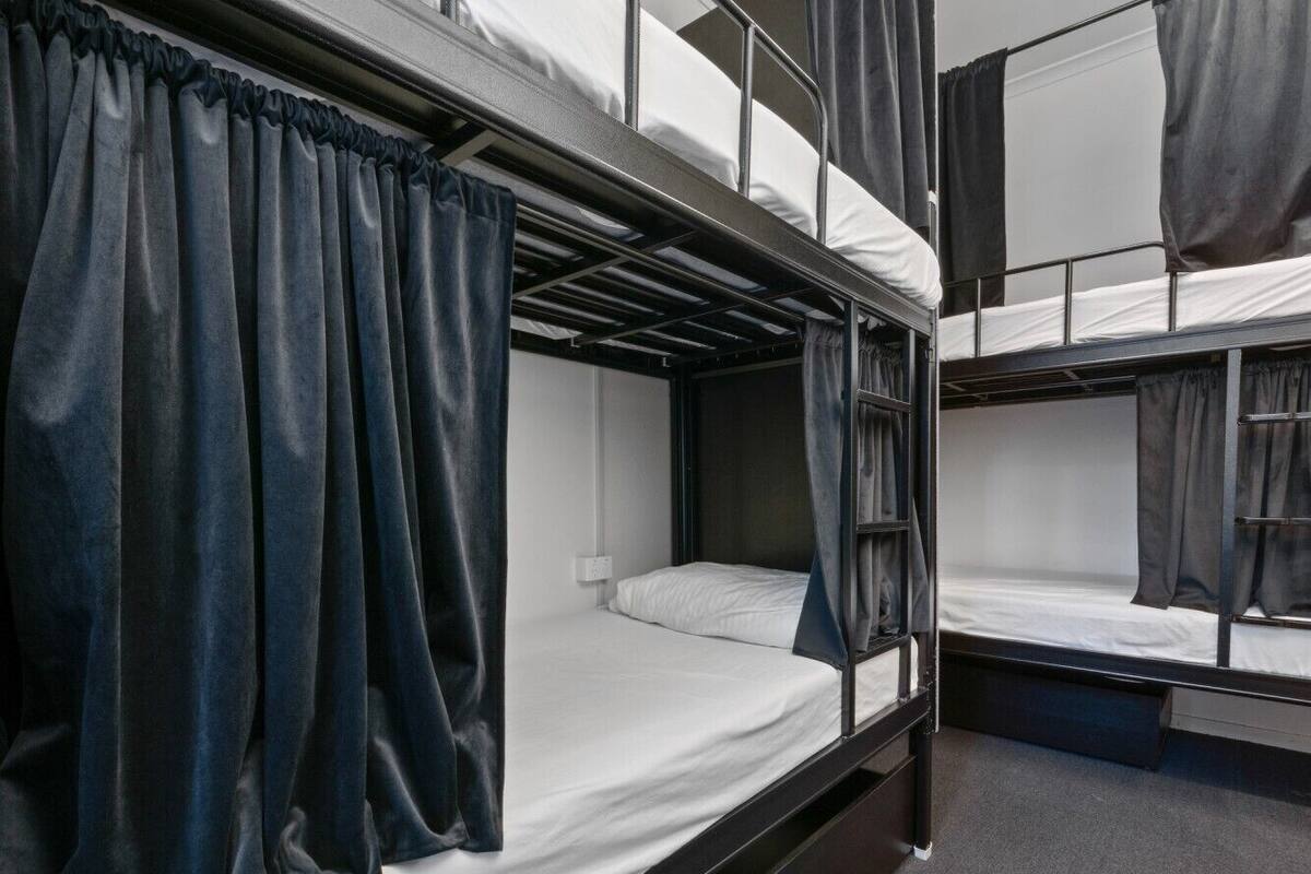 Habitación con literas, cortinas, una ventana y un enchufe.