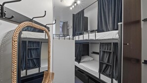 A bunk room with two beds, a mirror, and a wardrobe.