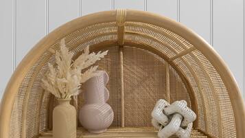 A rattan chair with a woven backrest and seat, a vase with dried plants, and a white ceramic vase.