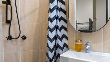 A bathroom with a shower, a sink, a mirror, and a toilet.