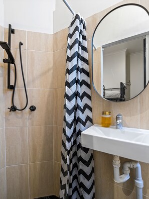 A bathroom with a shower, a sink, a mirror, and a toilet. - Azzurro Pod Hotel Central Sydney (Surry Hills)