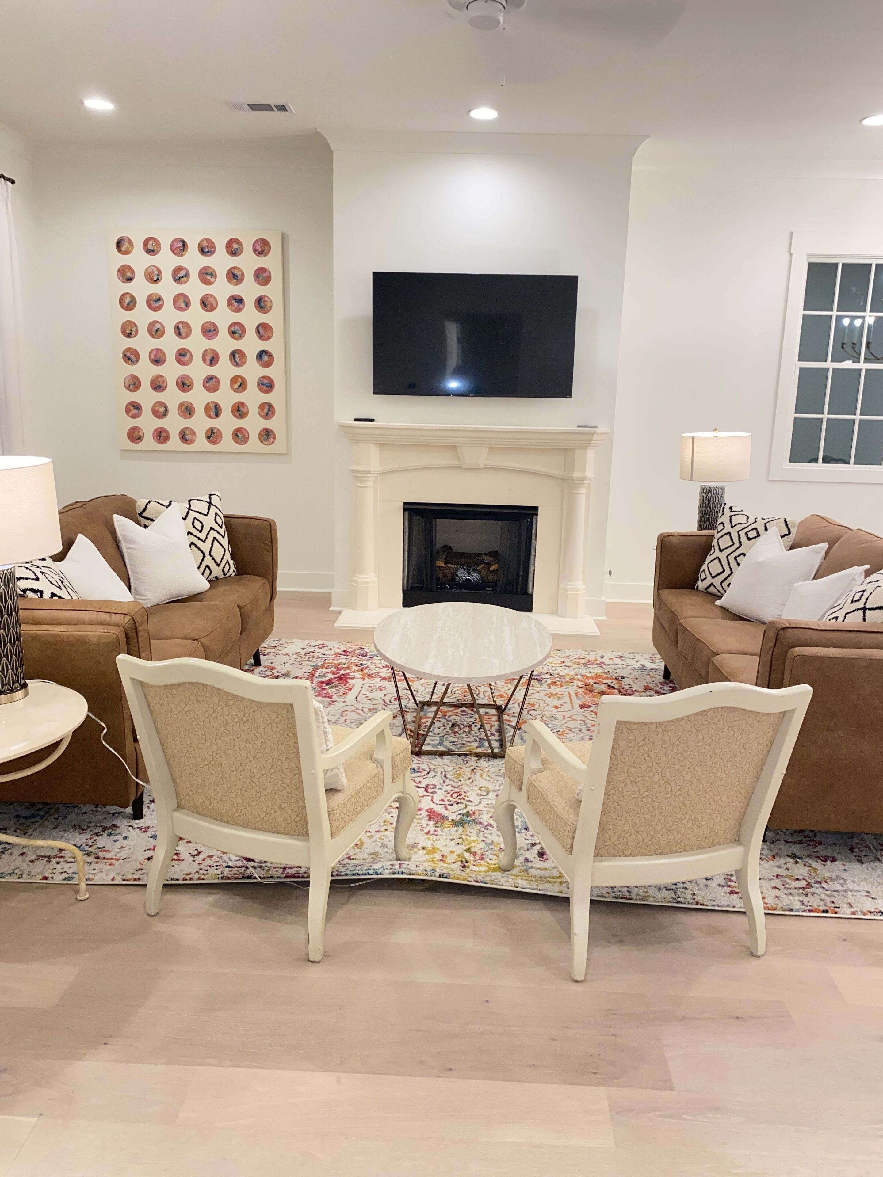 A living room with a fireplace, two sofas, a coffee table, and a TV mounted above the fireplace.