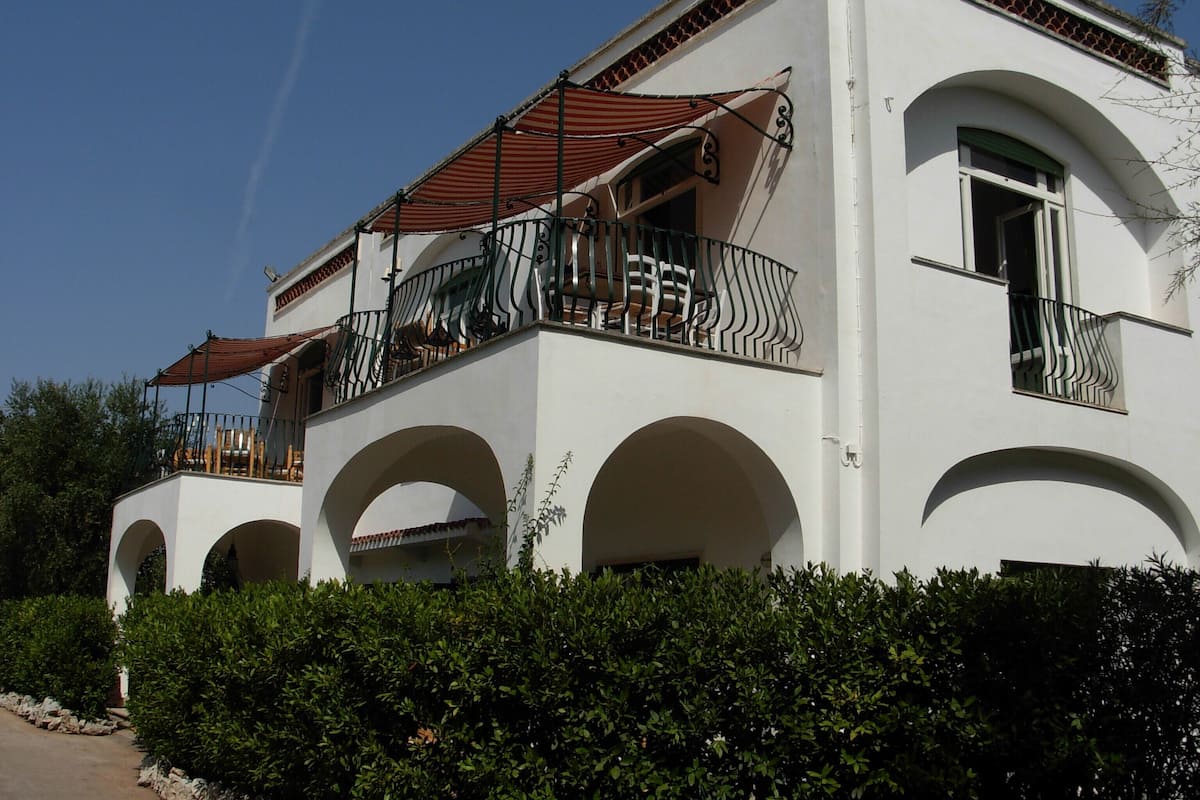 A two-story building with a balcony, arched windows, and a red roof.