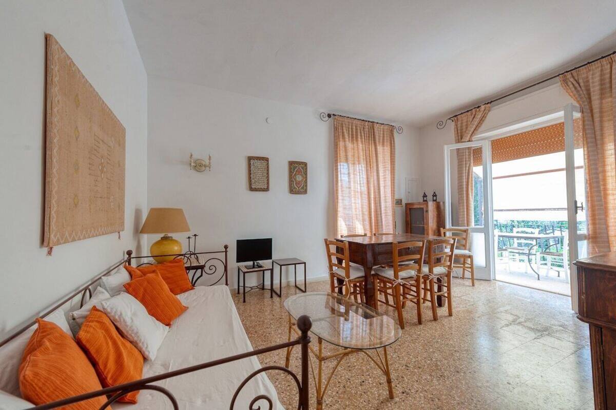 A room with a bed, a sofa, a dining table with chairs, a TV, and a balcony with a view.