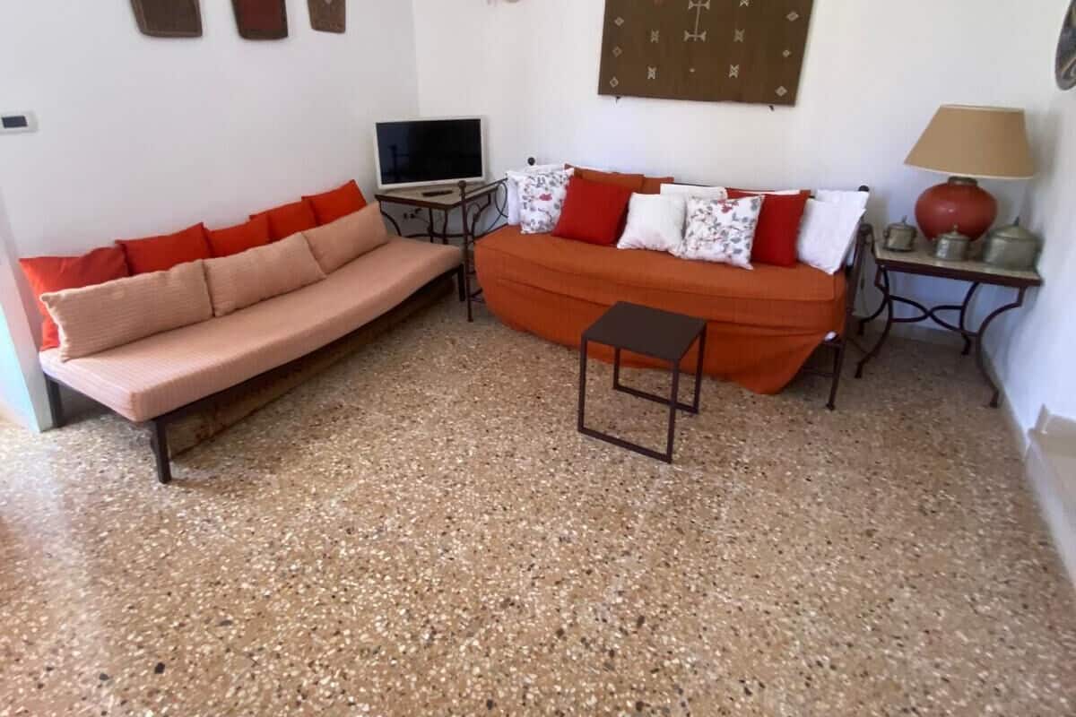 A living room with a sofa, a small table, a TV, and decorative wall art.