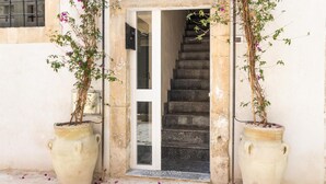 A staircase leading to a door, flanked by two large pots with climbing plants. - Bowie's Rooms (Noto)