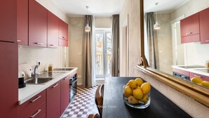 A modern kitchen with red cabinets, a checkered floor, and a bowl of lemons on the table. - Bowie's Rooms (Noto)