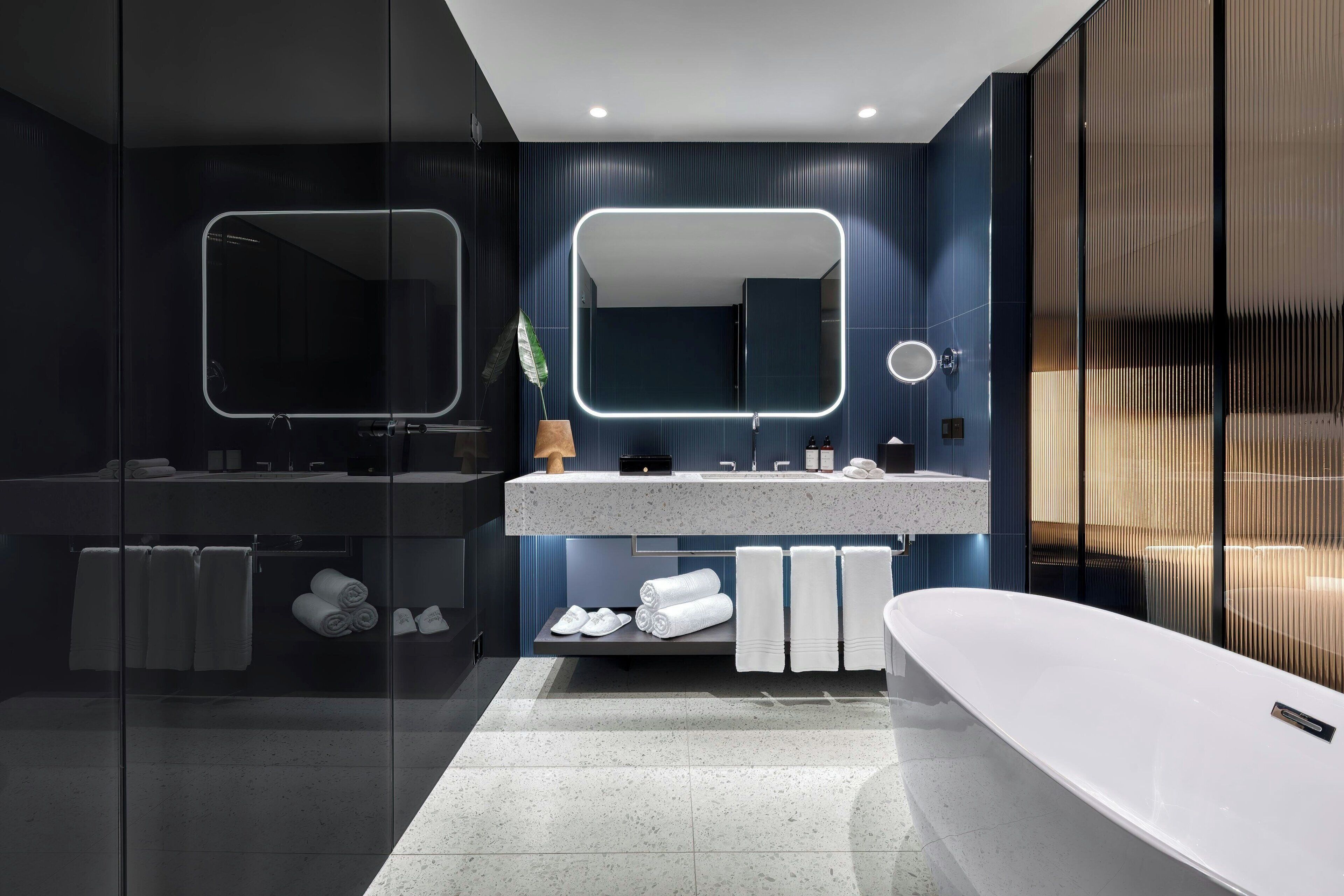 Een moderne badkamer met een douchecabine van glas, een vrijstaand bad en een wastafel met spiegel.