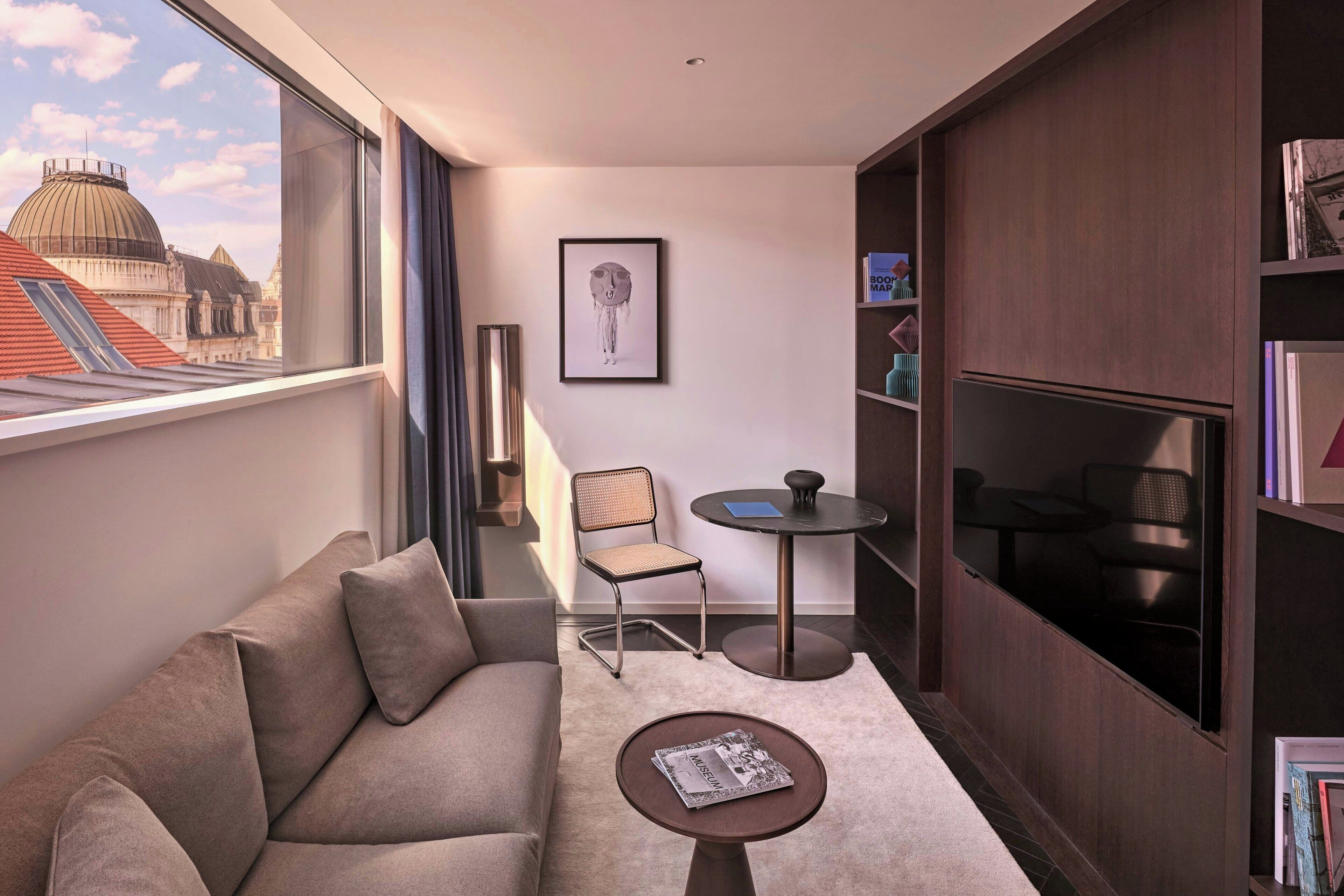A modern living room with a sofa, a small round table, a chair, and a bookshelf.