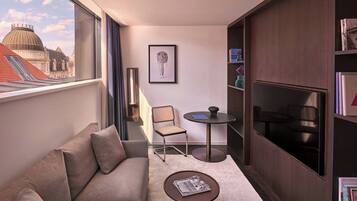A modern living room with a sofa, a small round table, a chair, and a bookshelf.