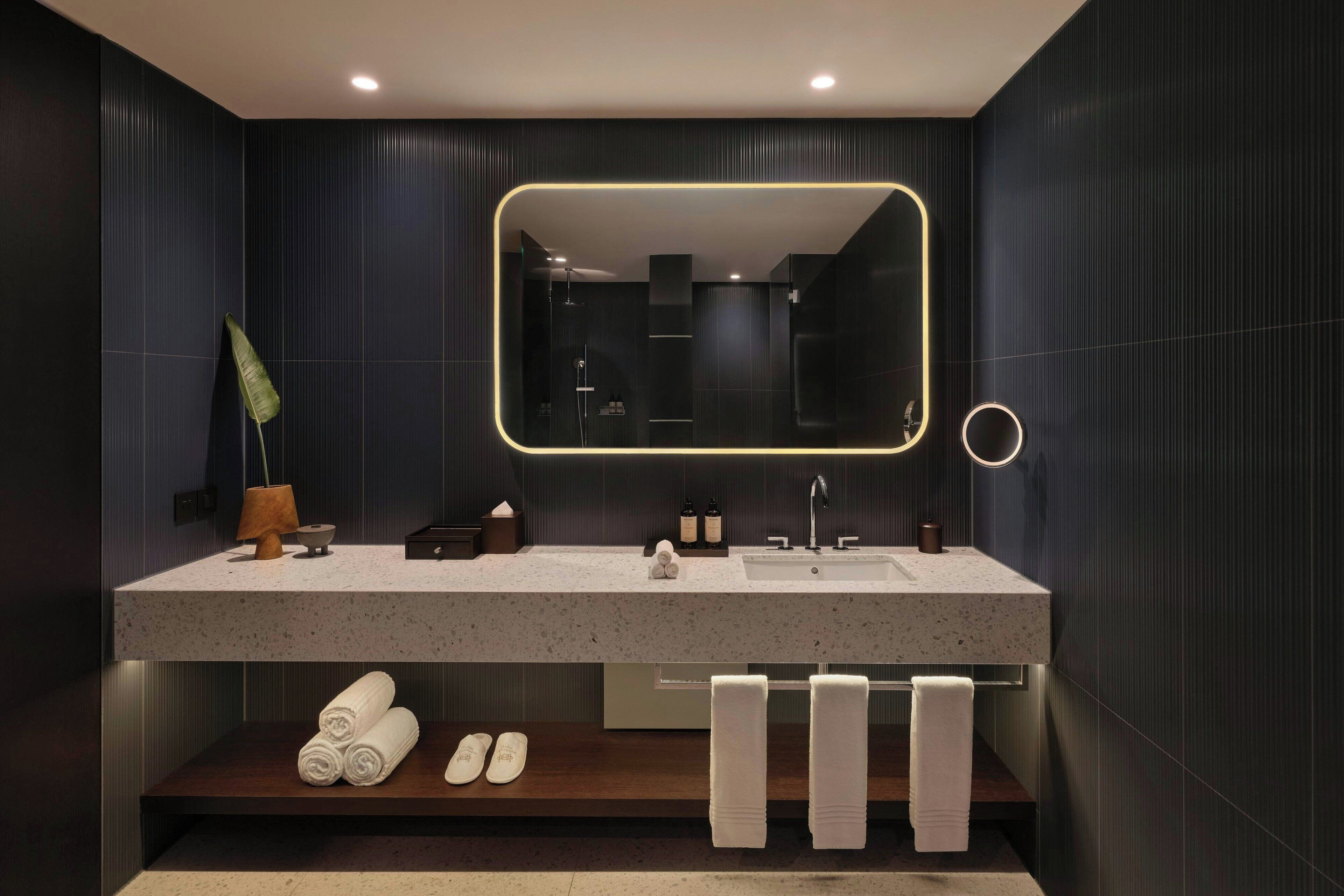 A modern bathroom with a large mirror, a sink, and a towel rack.