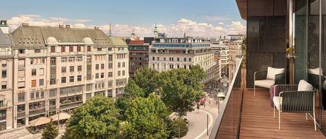 Een balkon met uitzicht op een stadsbeeld, inclusief gebouwen en bomen.