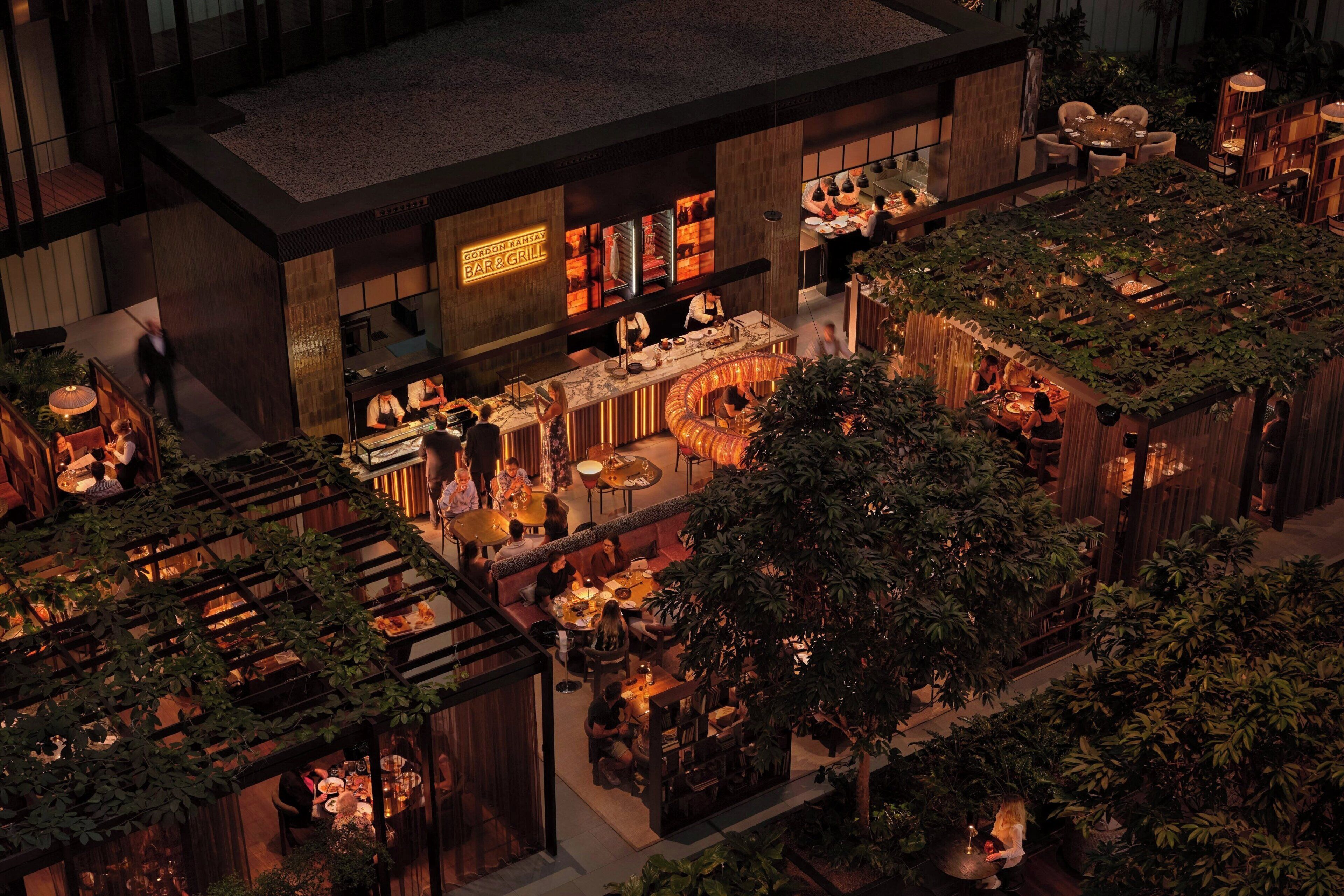 Un restaurante en la azotea con mesas al aire libre, rodeado de follaje y arquitectura moderna.