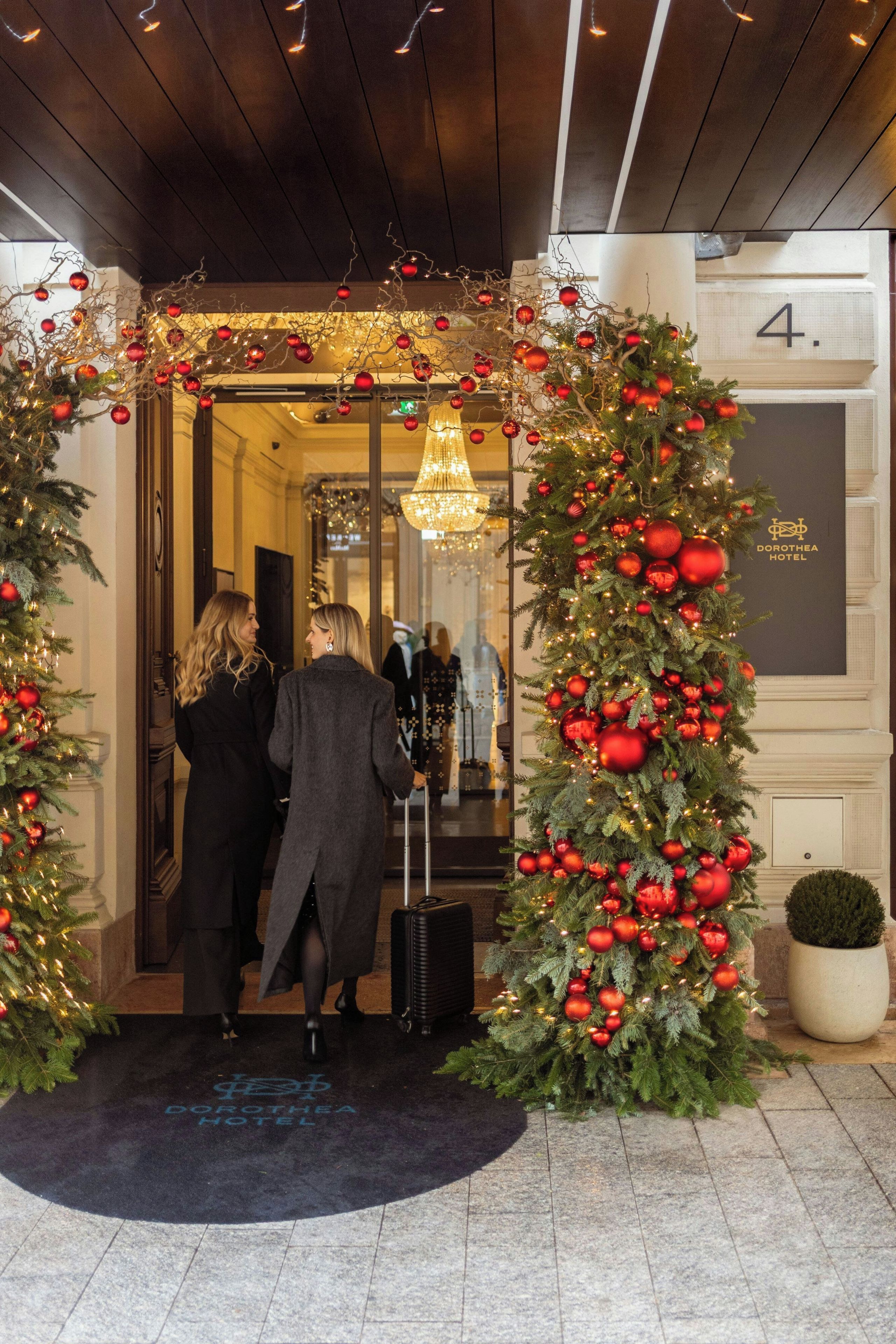 Entrada de hotel con un árbol de Navidad decorado con adornos y luces rojas.