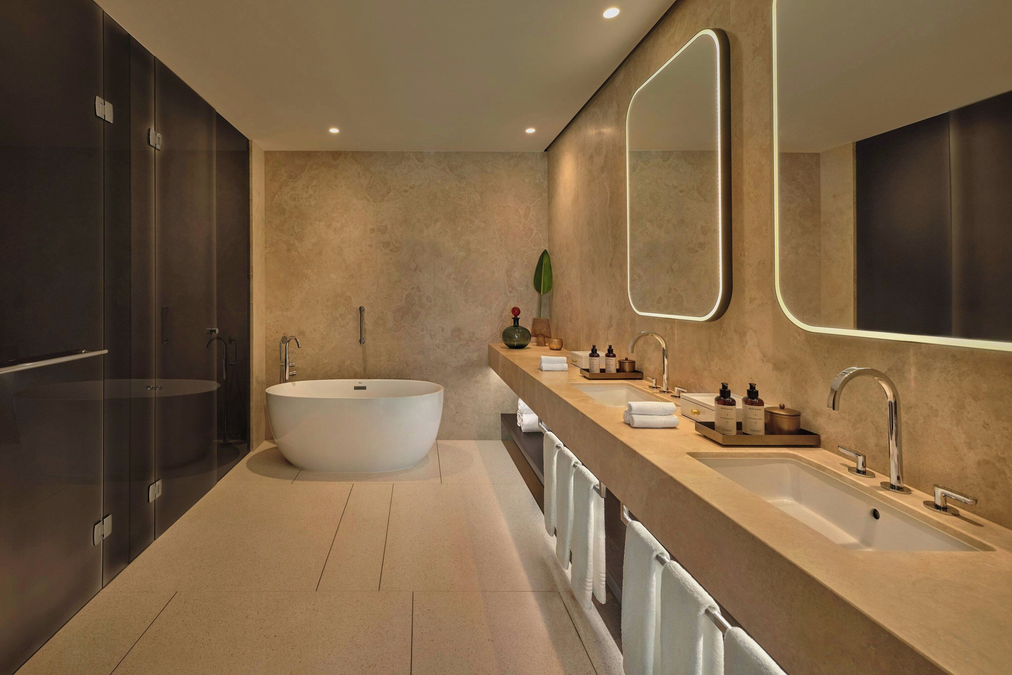 A modern bathroom with a freestanding bathtub, a double sink vanity, and a large mirror.