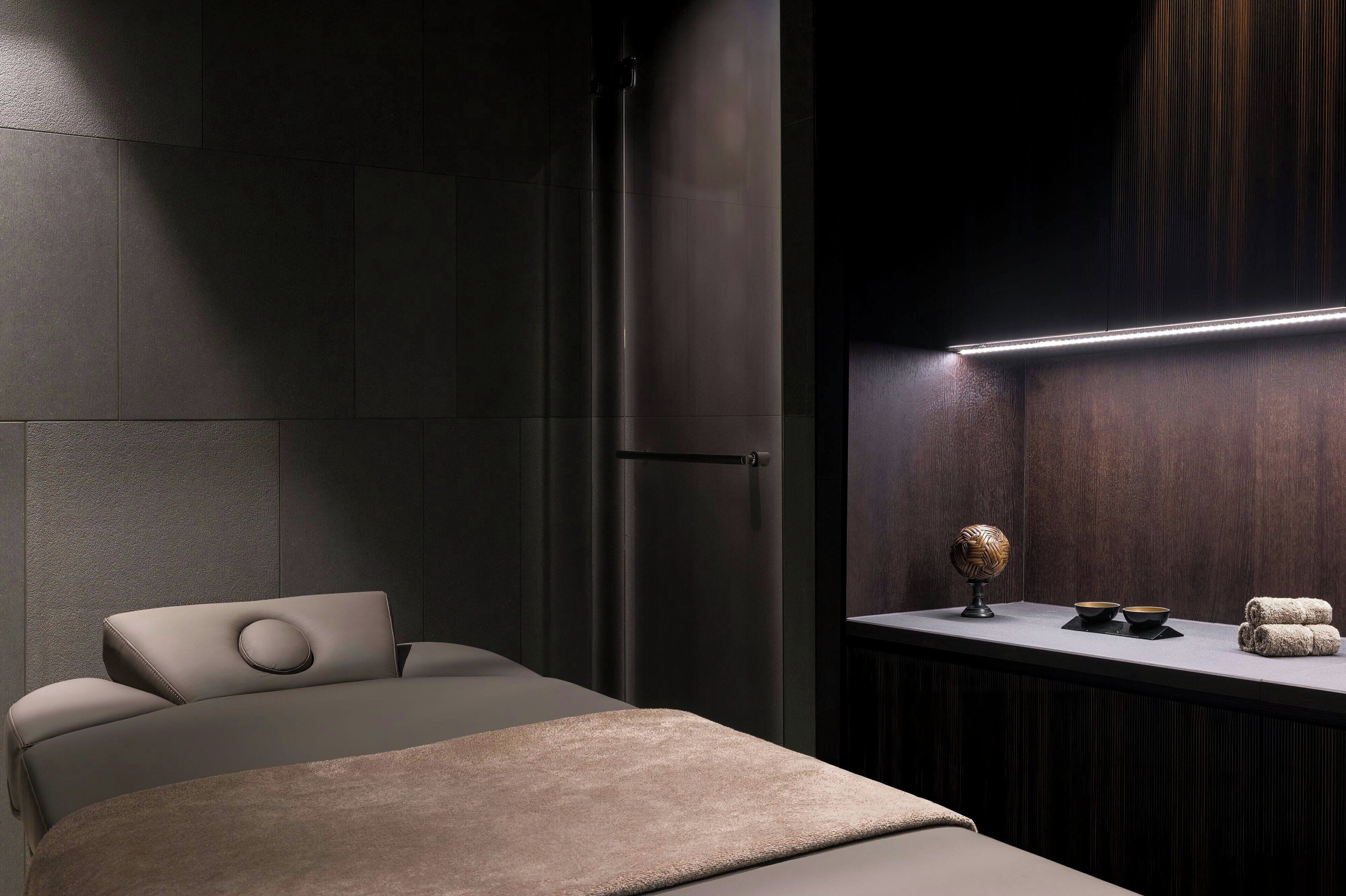 Un baño moderno con tocador de madera oscura, un perchero y un pequeño objeto decorativo sobre la encimera.