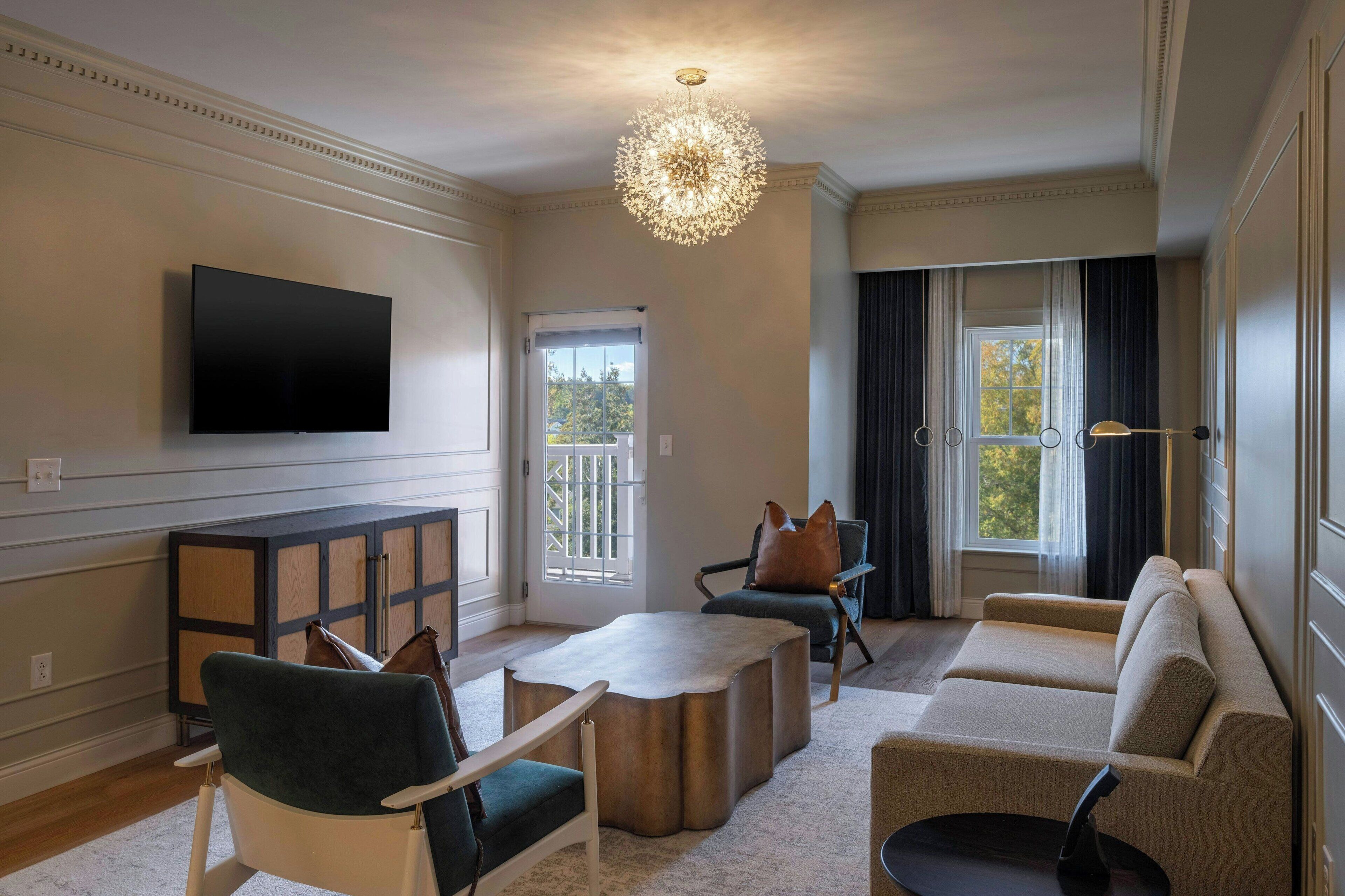 A living room with a flat-screen TV, a chandelier, a sofa, and a coffee table.