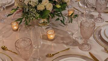 Una mesa dispuesta para un evento formal, con cristalería, cubiertos y un centro de mesa floral.