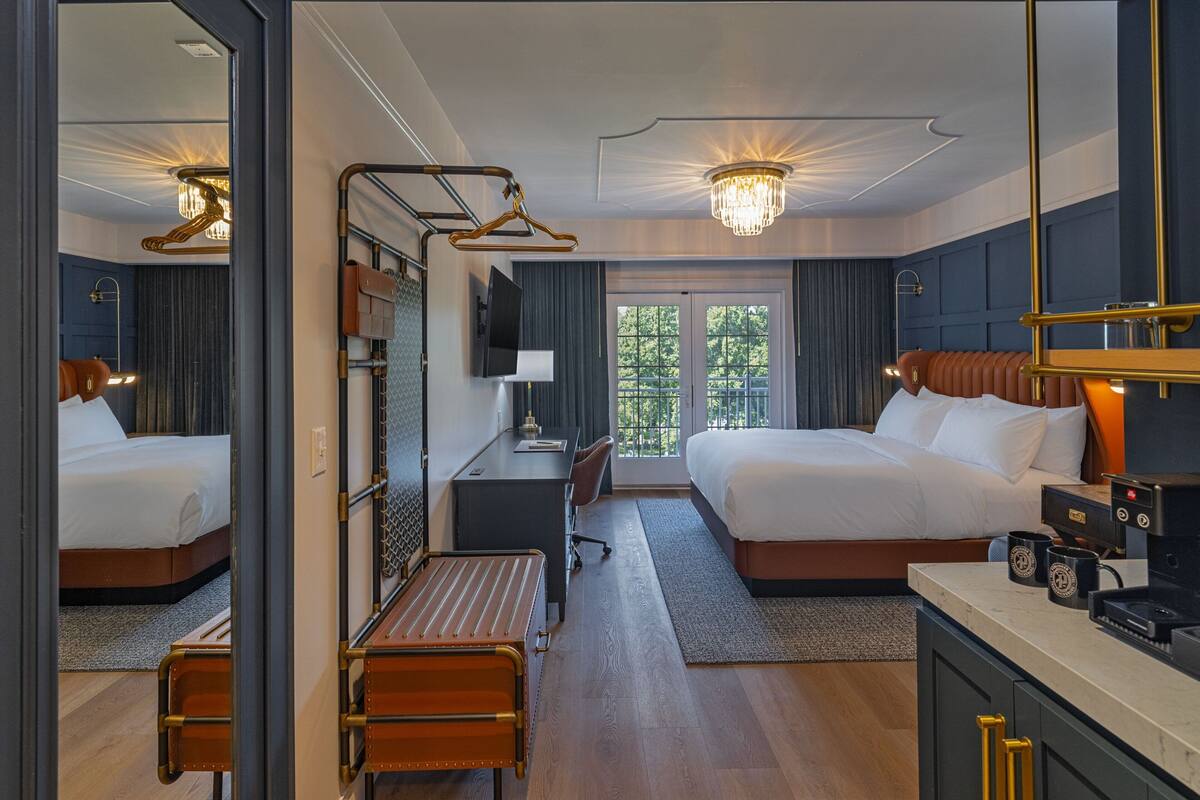 Ett hotellrum med två sängar, ett skrivbord, en stol, en kaffebryggare och utsikt över omgivningarna.