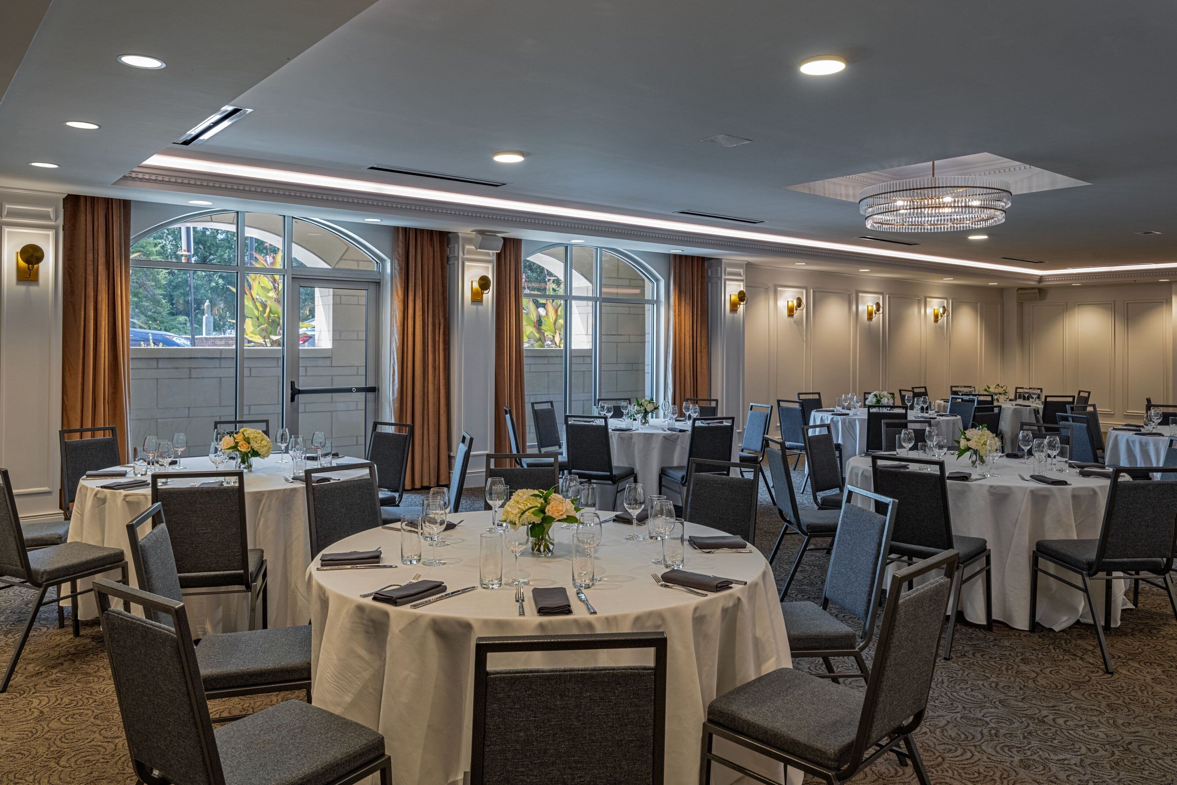 A conference room with multiple tables, chairs, and a chandelier.