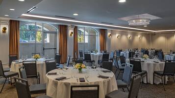 A conference room with multiple tables, chairs, and a chandelier.