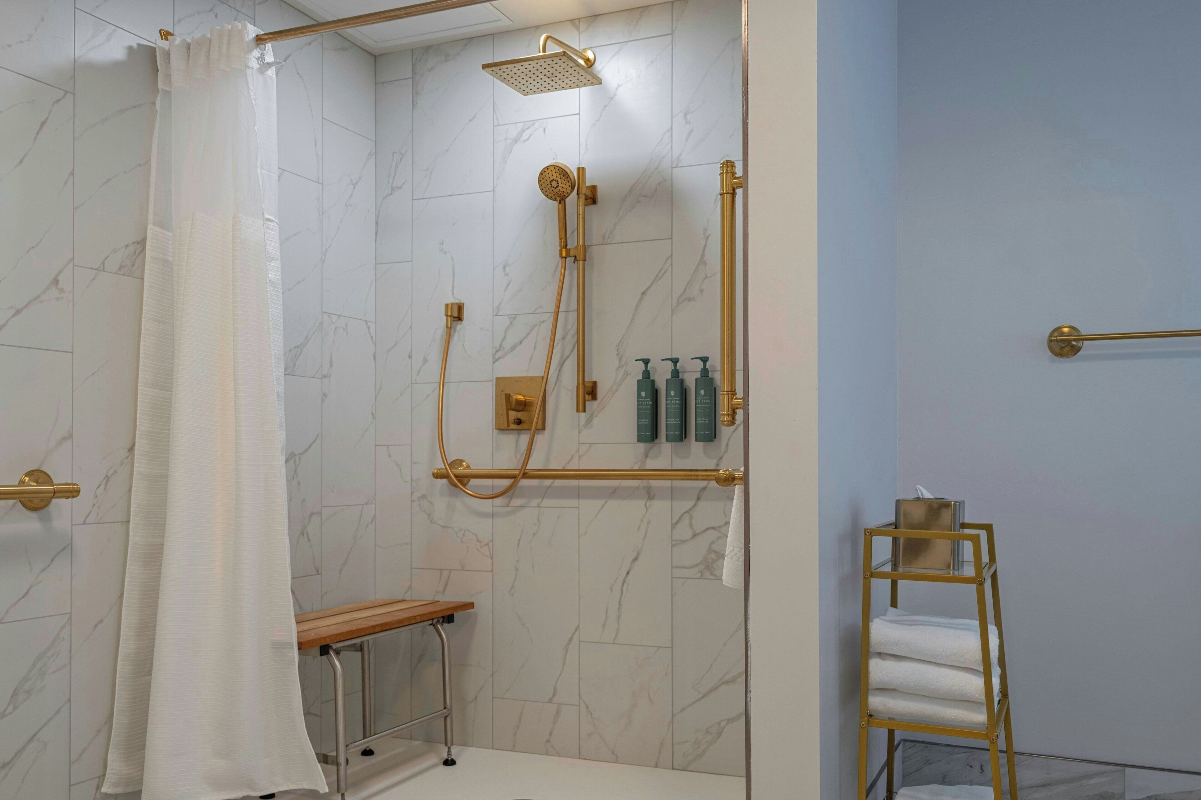 Un baño moderno con ducha, un banco y un perchero para toallas.