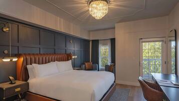 Una habitación de hotel moderna con una cama grande, un escritorio y una araña.